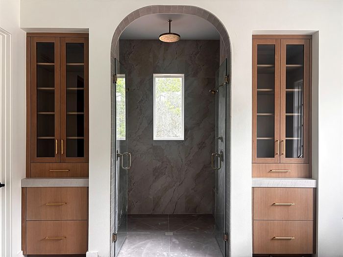 111 Bear Den Court &mdash; Primary bath with arched marble shower flanked by glass cabinets
